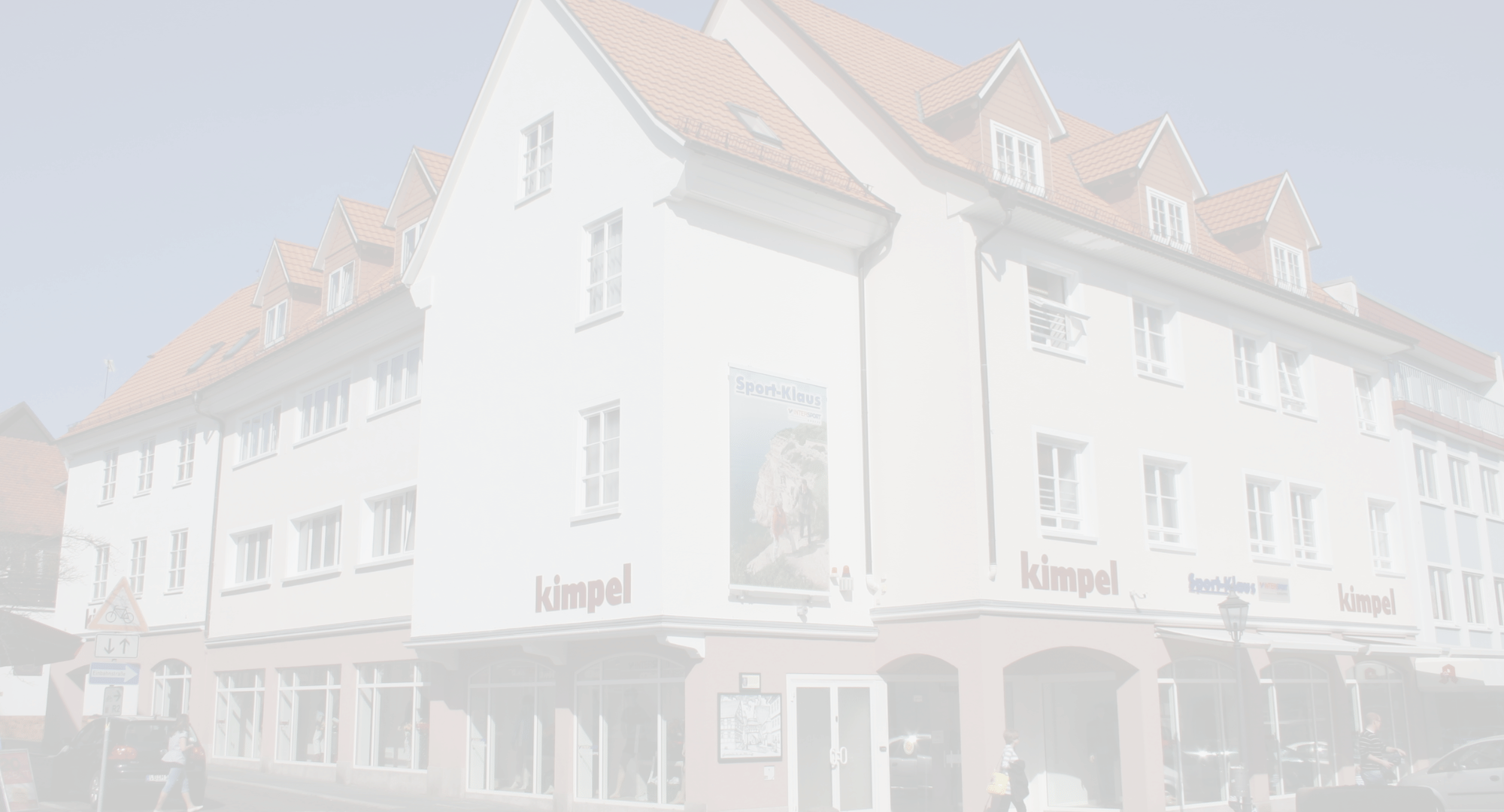 Außenansicht des Modehaus Kimpel in Lauterbach mit weißer Fassade, roten Ziegeldach und großer Schaufensterfront